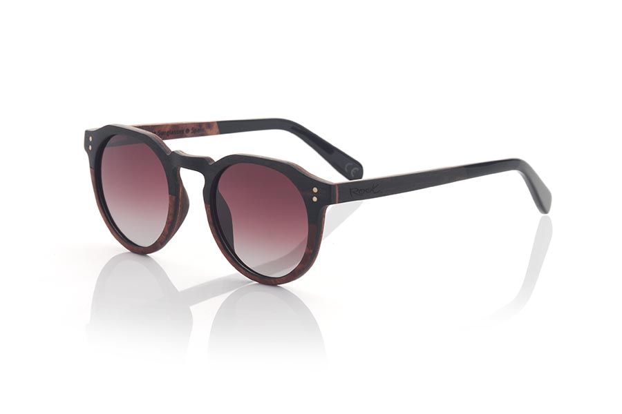 Wood eyewear of Ebony modelo IREM. IREM wooden sunglasses combine elegance and style. They are made entirely with a frame made of laminated EBONY wood on the upper part and Burr wood with a marbled appearance on the lower part and on the inside, while the temples are made of ebony wood on the outside and Burr wood on the inside. inside. It is rounded at the bottom and angular at the brow, making it suitable for both men and women. It is available in two gradient lens colors: brown and grey.
The finish on these sunglasses makes them unique and elegant, perfect for those looking for something different in their fashion accessories. In addition, being made of laminated wood, they are resistant and durable, and the combination of different wood tones adds a touch of style and originality. Front measurement: 141x51mm Caliber: 49 | Root Sunglasses® 